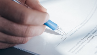 Personal Injury Lawyer Tulsa - Truskett Law Close-up of a hand holding a blue pen about to sign a document.